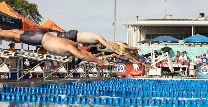 Male swimmers diving from starting blocks at the beginning of a freestyle race